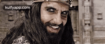 a man with a long beard and a crown is smiling .