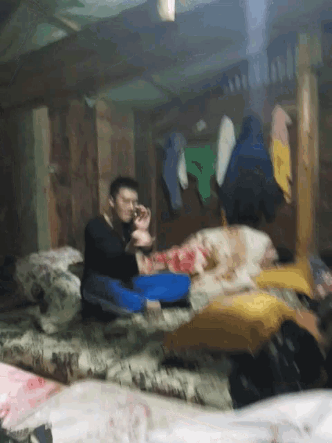 a blurry photo of a man sitting on a bed talking on a cell phone