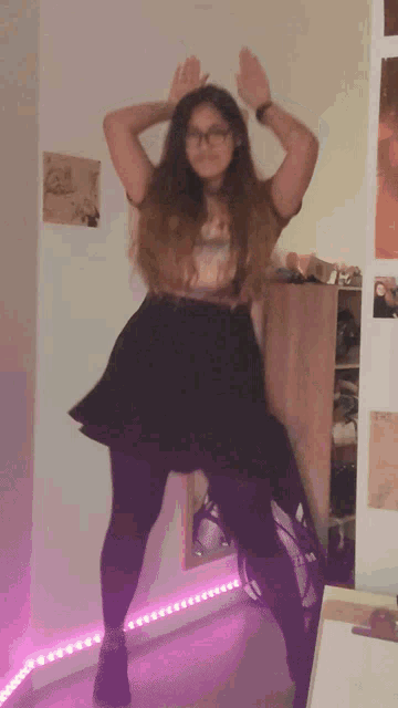 a woman in a black skirt and glasses is dancing