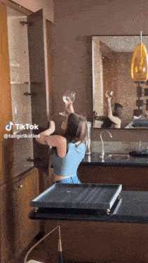a woman is holding a wine glass in front of a mirror in a bathroom .