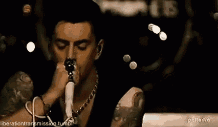 a man with tattoos is singing into a microphone .