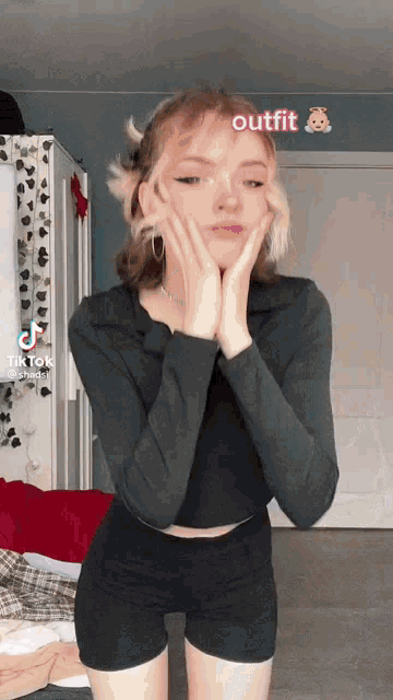 a girl wearing a crop top and shorts is making a funny face