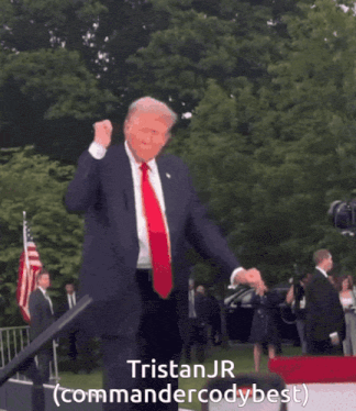 a man in a suit and tie is dancing in front of a sign that says tristan jr