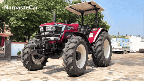 a red and white tractor is parked in front of a namaste car ad