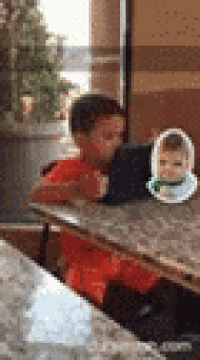 a young boy is sitting at a table with a tablet and a picture of a baby on it .
