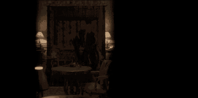 a dark room with a couch a table and a lamp