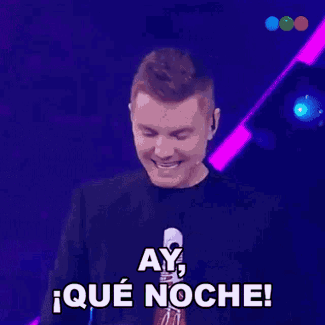 a man wearing a black shirt with a skull on it says ay qué noche