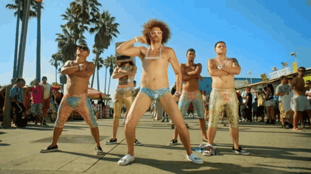 a group of men are dancing on a sidewalk in front of a sign that says ' the ice cream shop '