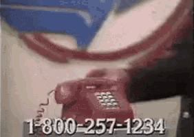 a man is talking on a red telephone with the number 1-800-257-1234 on the bottom