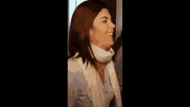 a woman wearing a scarf around her neck is laughing
