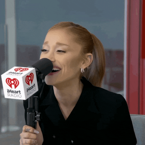 a woman singing into a microphone that says iheart radio on it