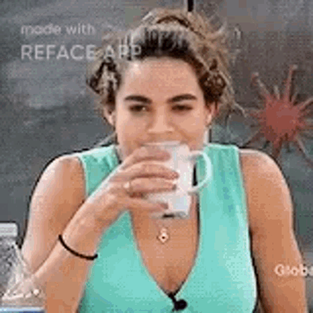 a woman in a blue tank top is drinking from a glass .