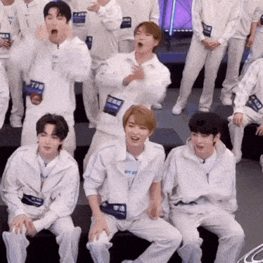a group of young men wearing white jackets with chinese writing on them are sitting on a bench