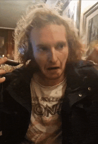 a man wearing a rolling stones t-shirt looks at the camera