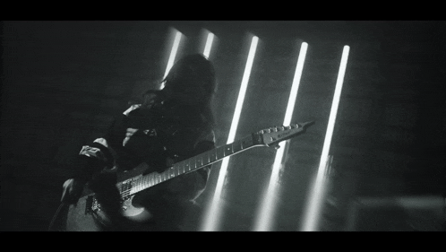 a black and white photo of a man playing a guitar with a yamaha logo on his shirt