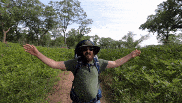 a man with his arms outstretched is walking through a field of ferns