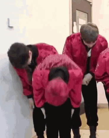a group of people in red jackets are kneeling down in a hallway .