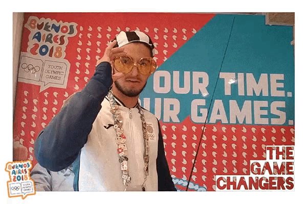a man wearing sunglasses stands in front of a sign that says our time our games