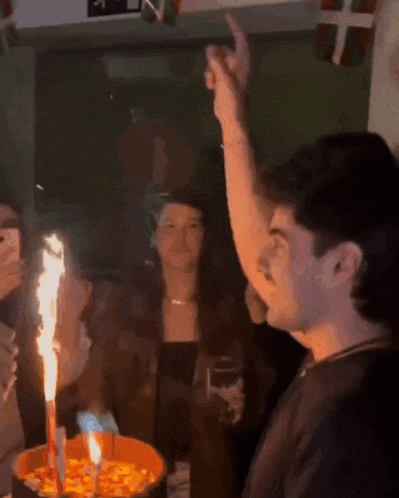 a group of people are celebrating a birthday with a cake and a candle