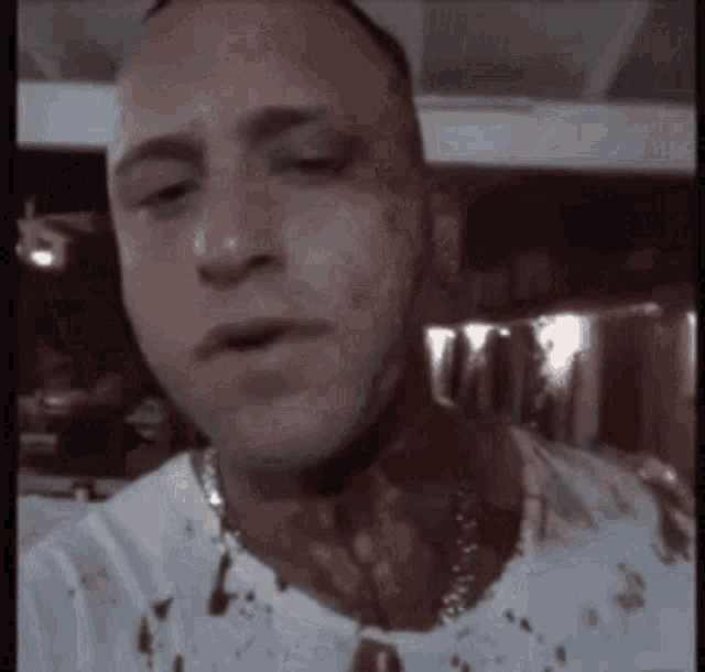 a man with blood on his shirt and neck is taking a selfie