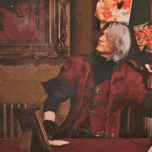 a man in a red leather jacket is sitting in front of a painting