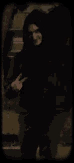 a man in a hooded jacket is standing in the dark .