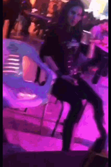 a blurry picture of a woman dancing in a dark room with purple lights