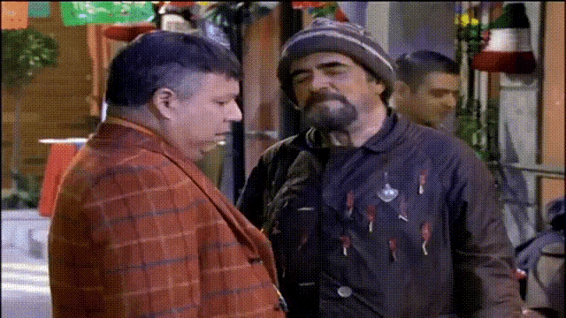 a man with a beard is talking to another man with a hat on