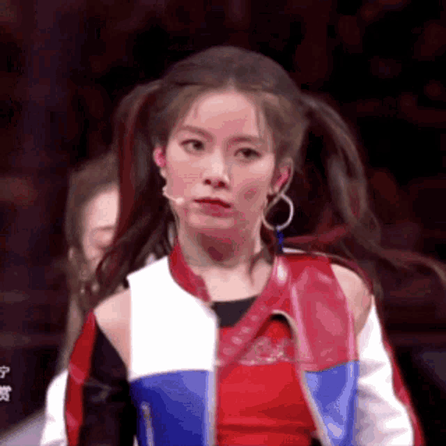 a woman in a red , white , and blue jacket is standing in front of a microphone .