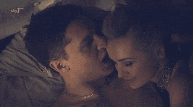 a man and a woman are kissing on a bed in front of a sign that says sky