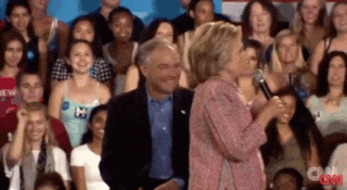 a woman is speaking into a microphone in front of a crowd with cnn on the bottom right