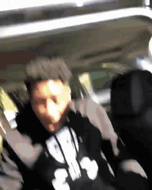 a man in a hoodie with the number 3 on it is sitting in the back of a car