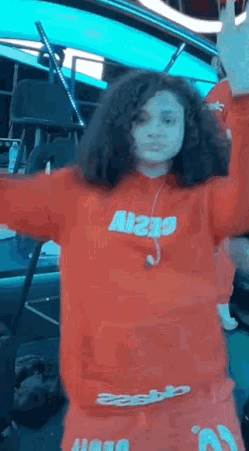 a young girl in a red hoodie is dancing on a stage .