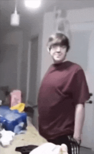 a man in a red t-shirt is standing in a room .