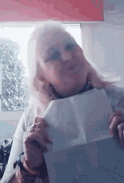 a woman is holding a piece of paper in her hand and looking at it .
