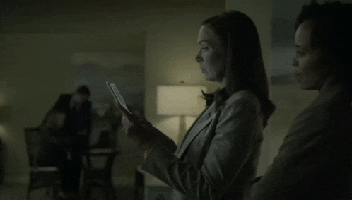 a woman looking at a piece of paper while another woman looks on
