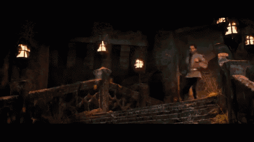 a man standing on a set of stairs with lanterns hanging from the ceiling