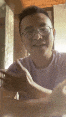 a young man wearing glasses and a purple shirt is smiling