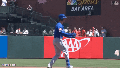 a baseball player stands on a field in front of a sports bay area sign