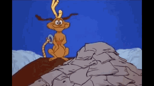 a cartoon character is sitting on top of a pile of blankets .