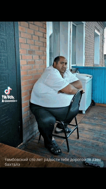 a very fat man is sitting in a chair in front of a brick wall