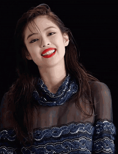 a woman wearing red lipstick and a blue dress smiles for the camera