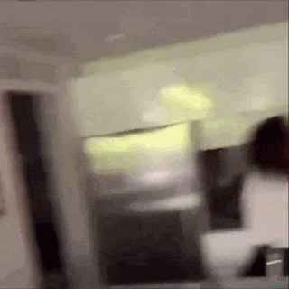 a blurry picture of a person standing in a room in front of a mirror .