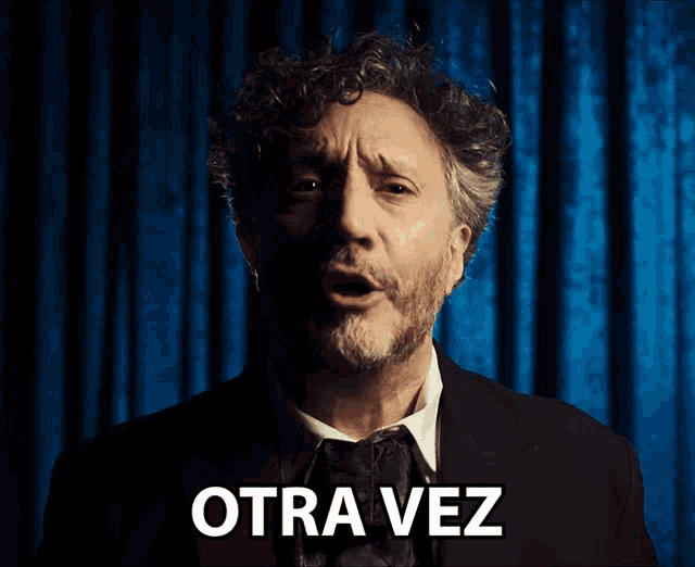 a man in a suit and tie says otra vez in white letters