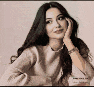 a woman wearing a watch and a pearl necklace has her hand on her chin