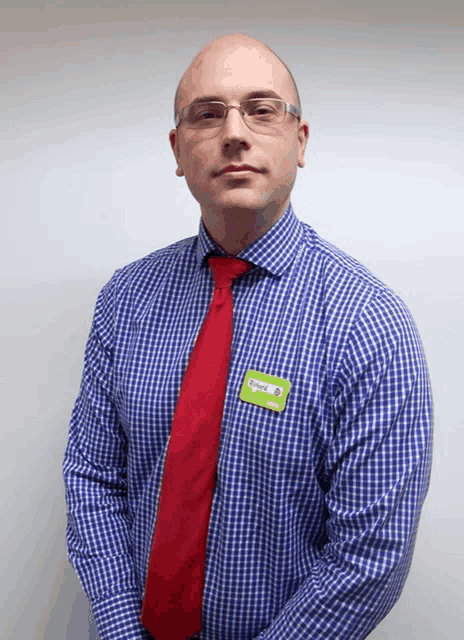 a man wearing a blue shirt and red tie has a name tag on his shirt that says ' ryan '
