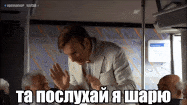 a man in a suit and tie is giving a speech in a bus