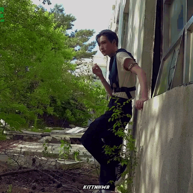a person leaning against a wall with the word kittnhwa written on the bottom