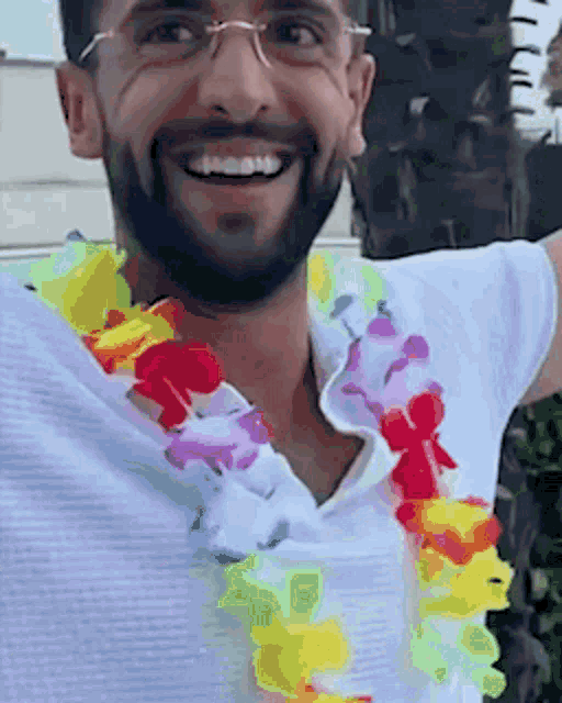 a man with a beard and glasses is wearing a colorful lei around his neck .