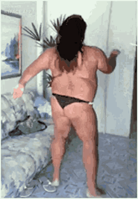 a man in a bikini is dancing in a room .